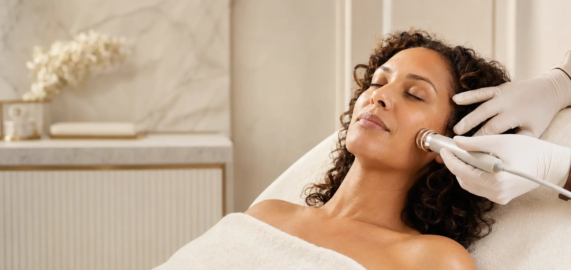 Woman receiving a calm, noninvasive facial treatment in a luxury treatment room